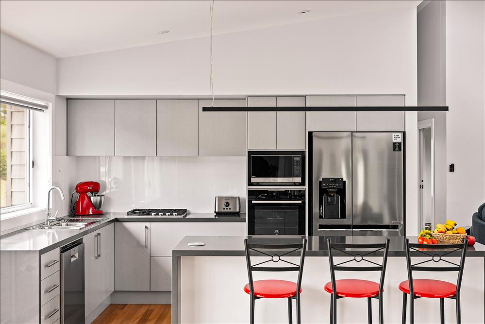 close up of kitchen showing breakfast bar with EssaStone waterfall ends, square set raking ceiling and appliances